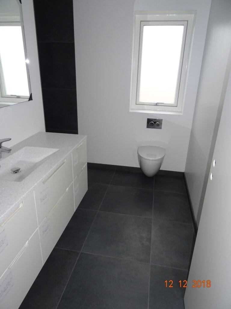 Moderne badeværelse med håndvask og væghængt toilet