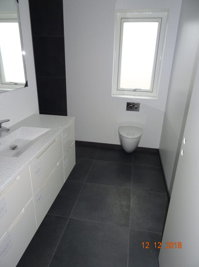 Moderne badeværelse med håndvask og væghængt toilet