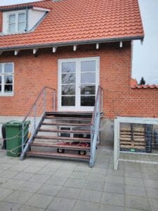 Murstenshus med trappe og rødt tegltag